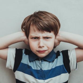 Autistischer Junge hält sich die Ohren zu